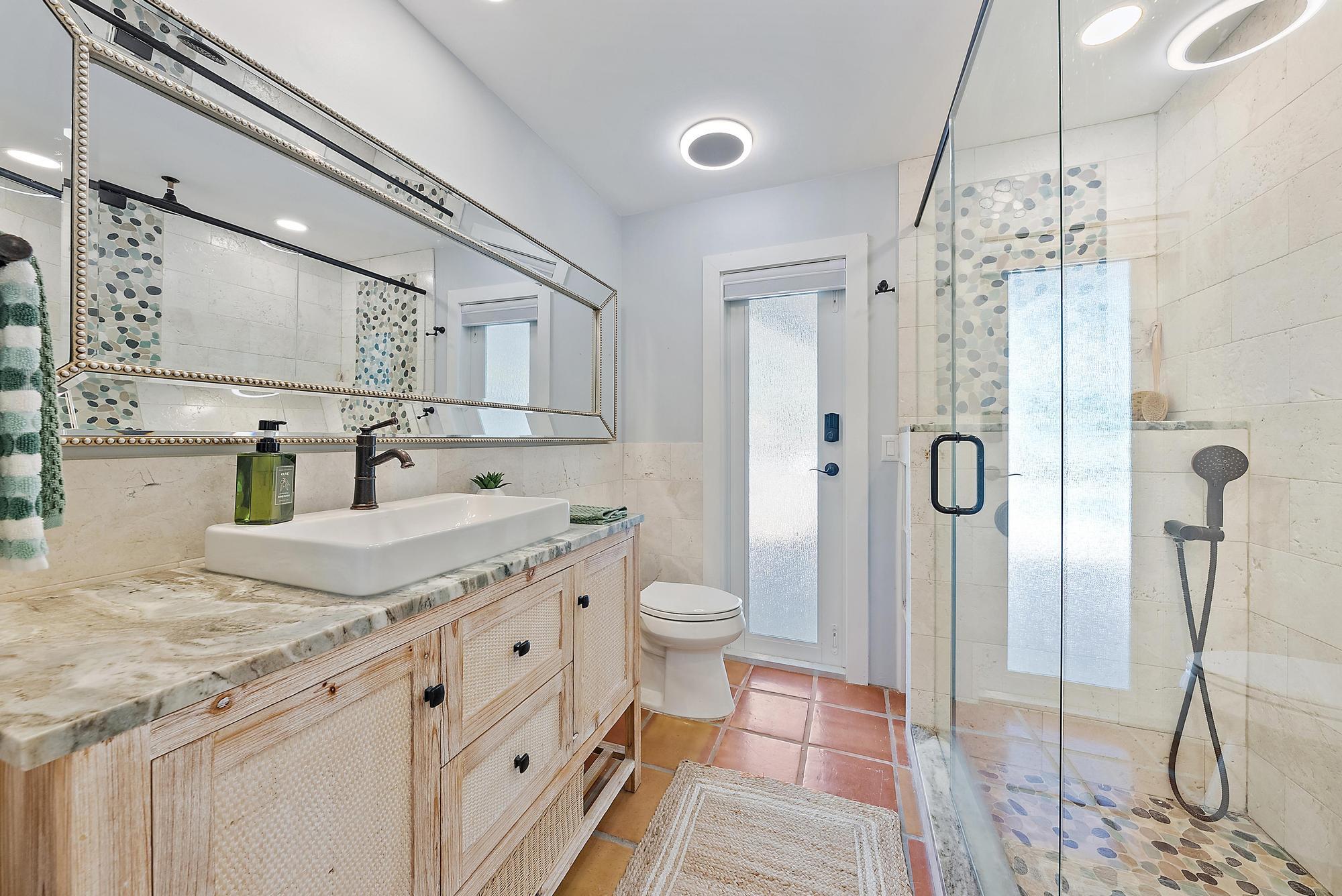 12821 Ellison Wilson Road North Palm Beach, FL 33408 - Photo 24 of 40 a bathroom with a granite countertop sink a toilet a mirror and shower