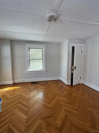 an empty room with wooden floor cabinets and a window