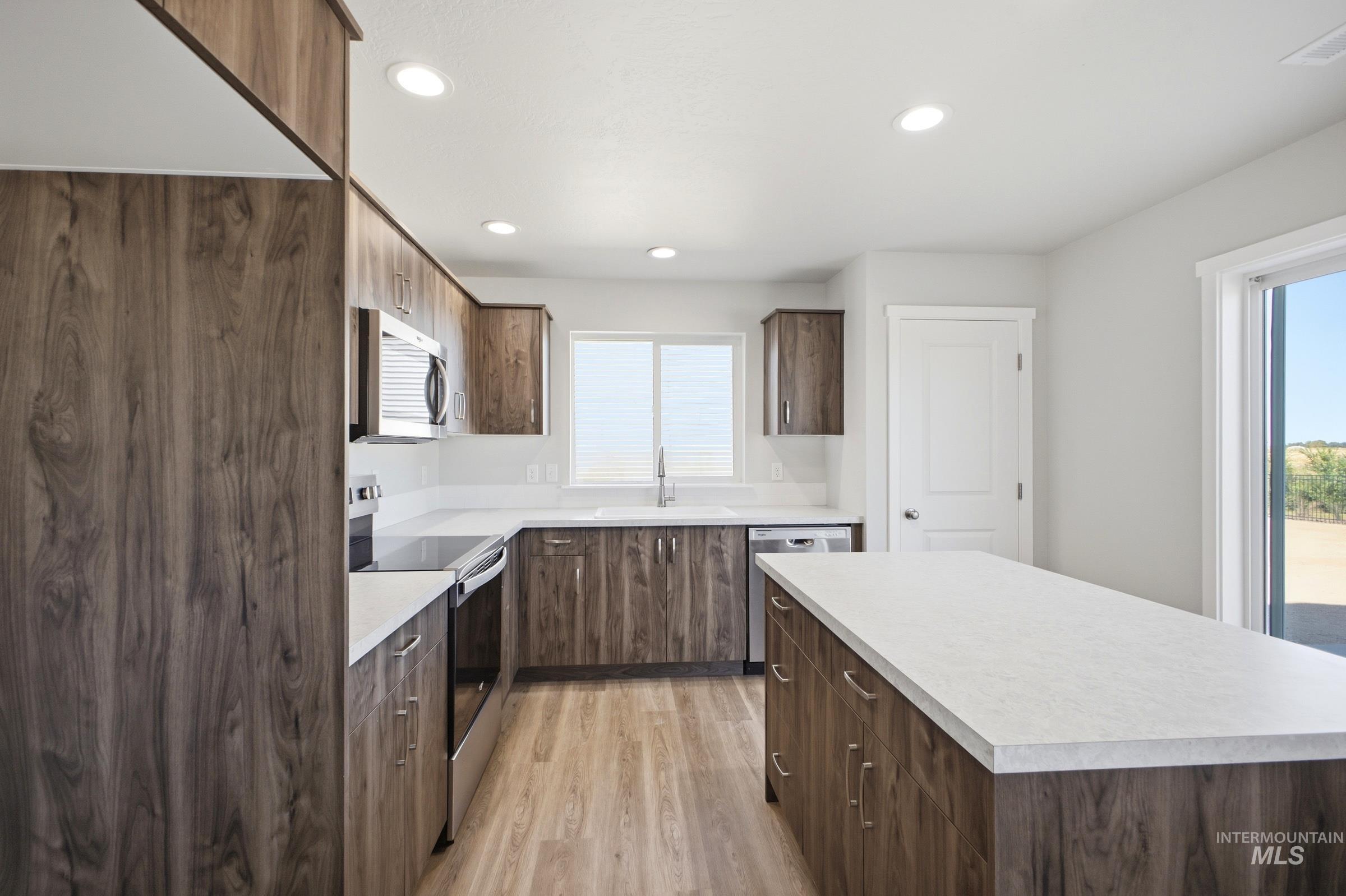 13325 Scrape Street Caldwell, ID 83607 - Photo 5 of 24 Modern kitchen featuring dark wood-finish cabinetry, white quartz countertops, stainless steel appliances, recessed lighting, and wood-finish flooring throughout