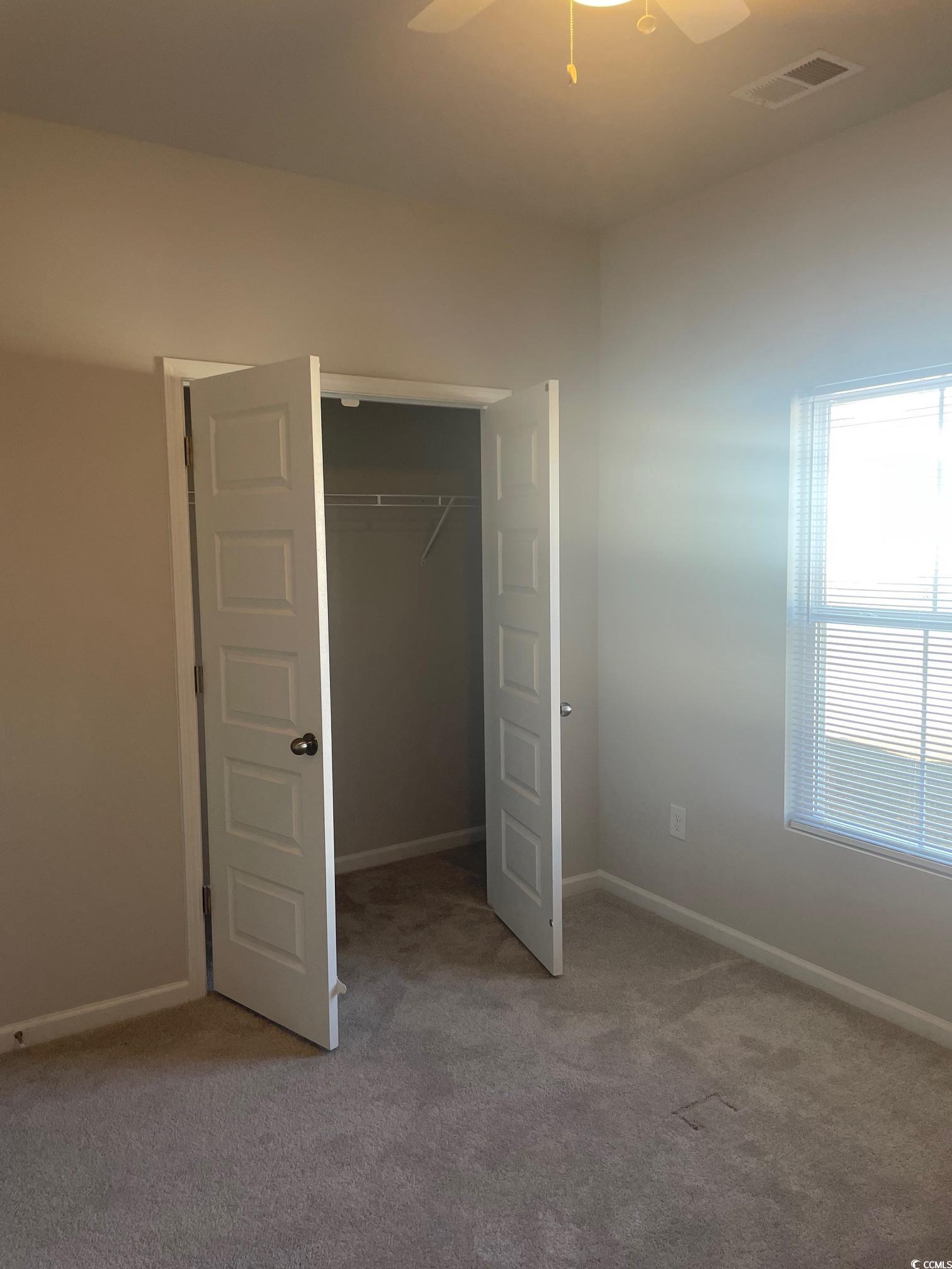 61 S Reindeer Road South Surfside Beach, SC 29575 - Photo 5 of 10 Unfurnished bedroom featuring light colored carpet, a closet, and ceiling fan
