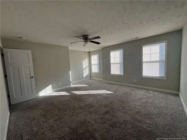 an empty room with windows and fan