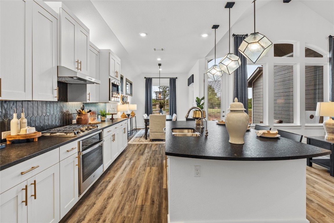128 Sandrock Trail Georgetown, TX 78633 - Photo 25 of 34 a large kitchen with stainless steel appliances granite countertop a sink a stove and a wooden floors