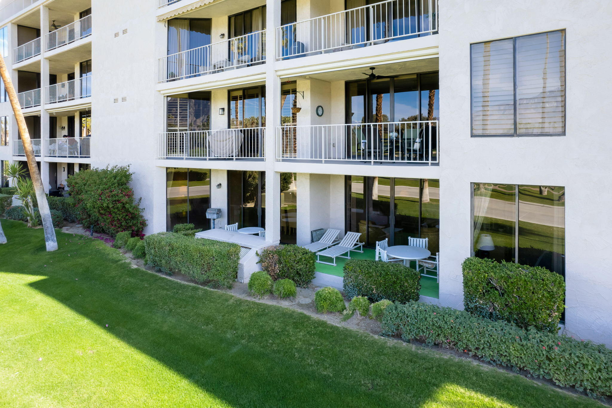 910 Island Drive, Unit 116 Rancho Mirage, CA 92270 - Photo 31 of 39 a view of an apartment with a large windows and a yard with plants and plants
