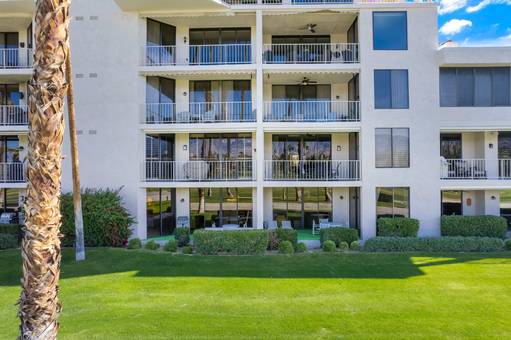 910 Island Drive, Unit 116 Rancho Mirage, CA 92270 - Photo 32 of 39 a front view of a building with a yard