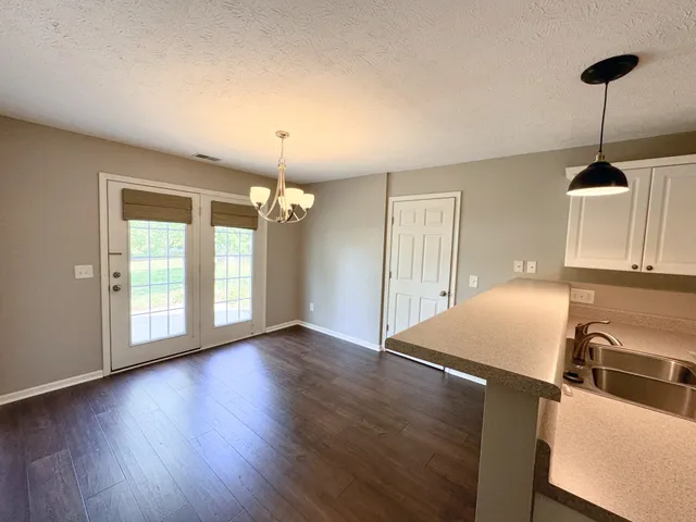 a kitchen with stainless steel appliances granite countertop a stove a sink dishwasher and a large refrigerator with wooden floor