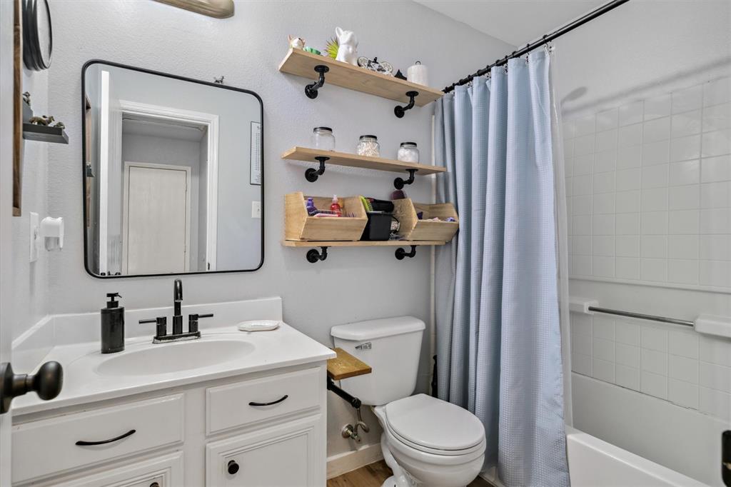 106 Rio Grande Drive Crandall, TX 75114 - Photo 33 of 40 a bathroom with a sink a toilet a mirror and shower curtain