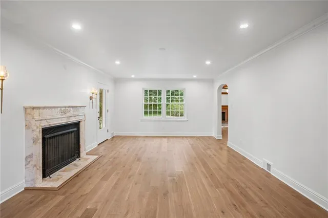 an empty room with wooden floor a fireplace and windows