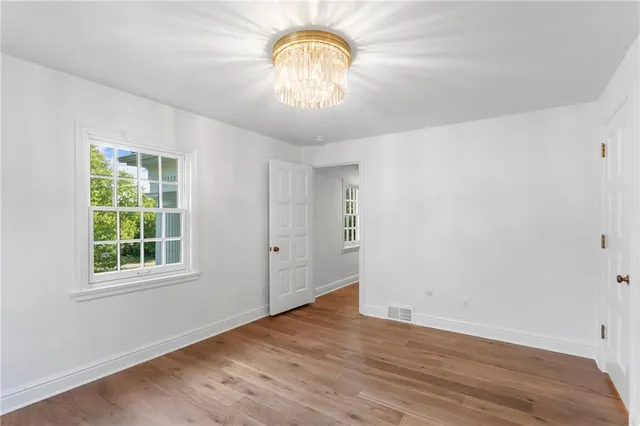 an empty room with wooden floor fan and windows