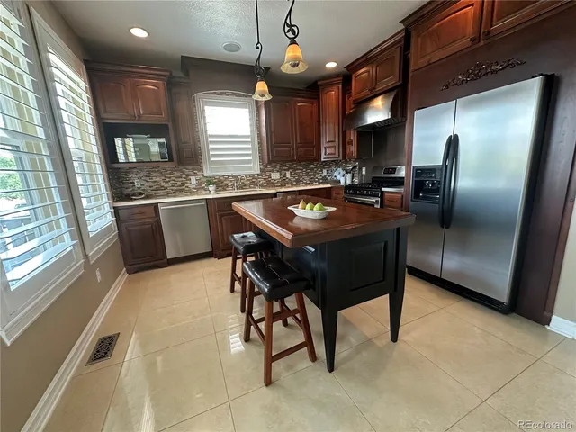 a kitchen with stainless steel appliances granite countertop a sink a stove and a refrigerator