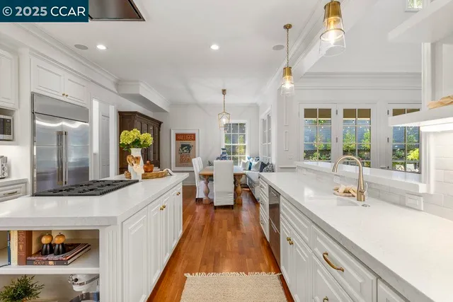 a large kitchen with stainless steel appliances a large counter top a stove a chimney a sink and a large window