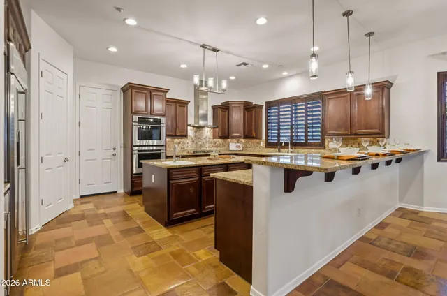 a kitchen with stainless steel appliances kitchen island granite countertop a refrigerator and a stove top oven