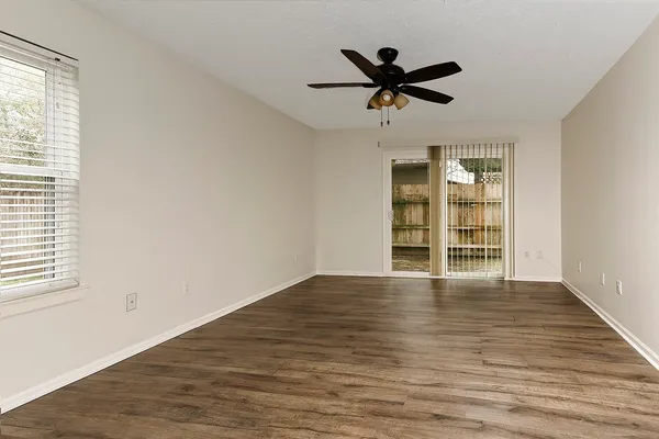 a view of empty room with wooden floor and window