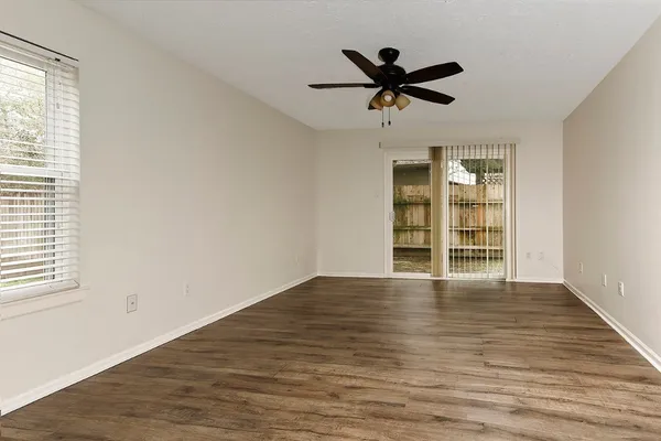 a view of empty room with wooden floor and window