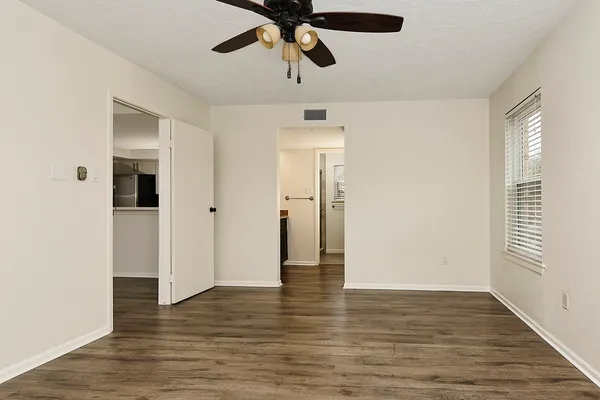 a view of an empty room with wooden floor and a ceiling fan