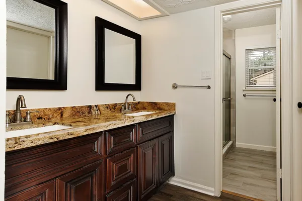 a bathroom with a granite countertop double vanity sink and mirror