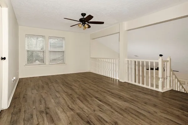 a view of empty room with wooden floor and fan