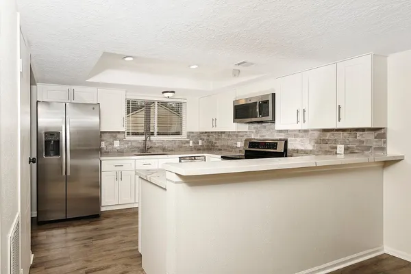 a kitchen with stainless steel appliances granite countertop a refrigerator a stove top oven a sink and dishwasher