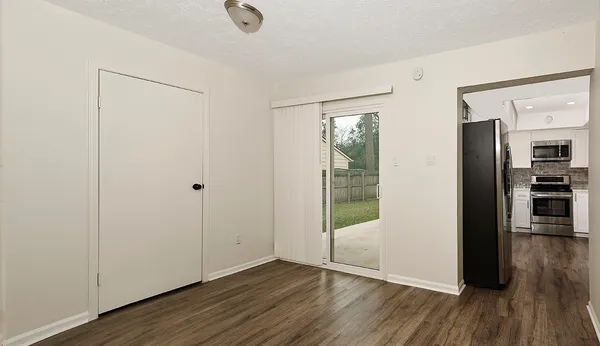 a view of an empty room with wooden floor and a window