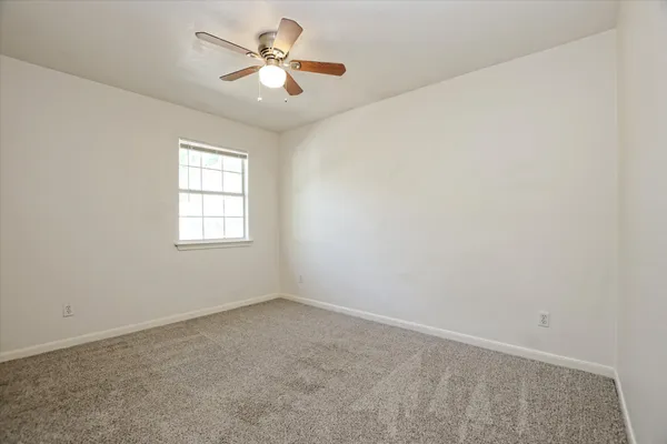 an empty room with a window and a fan