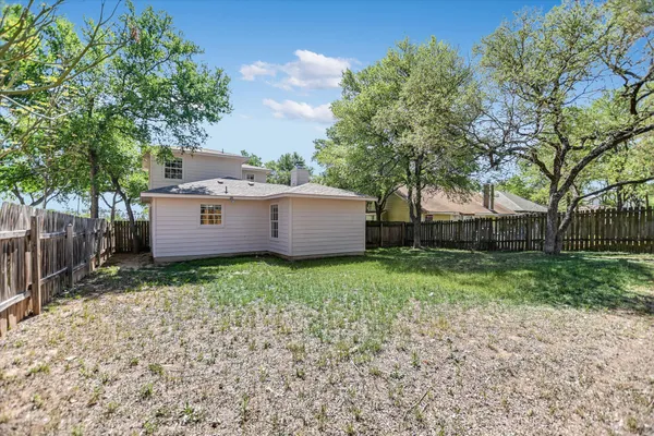 a view of a house with a yard and a large tree