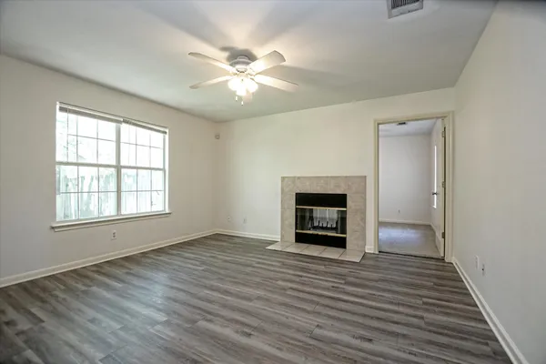 an empty room with wooden floor fan and windows