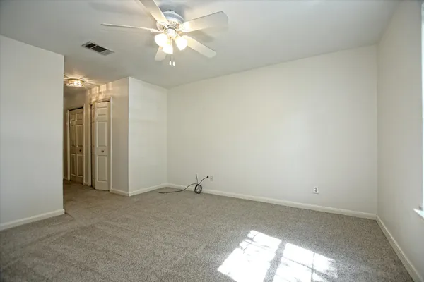 an empty room with a ceiling fan and a window