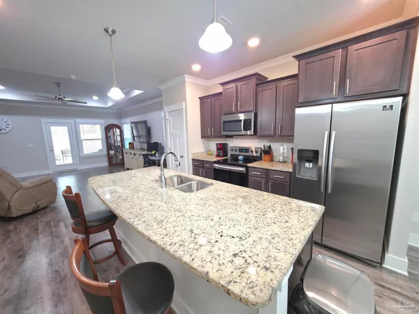 a kitchen with stainless steel appliances kitchen island granite countertop a table chairs and a refrigerator
