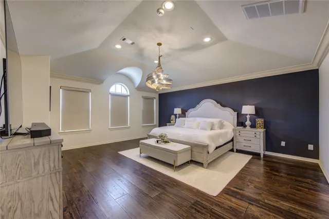 a spacious bedroom with a bed and a chandelier
