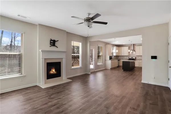 a view of a livingroom with a fireplace a ceiling fan and windows