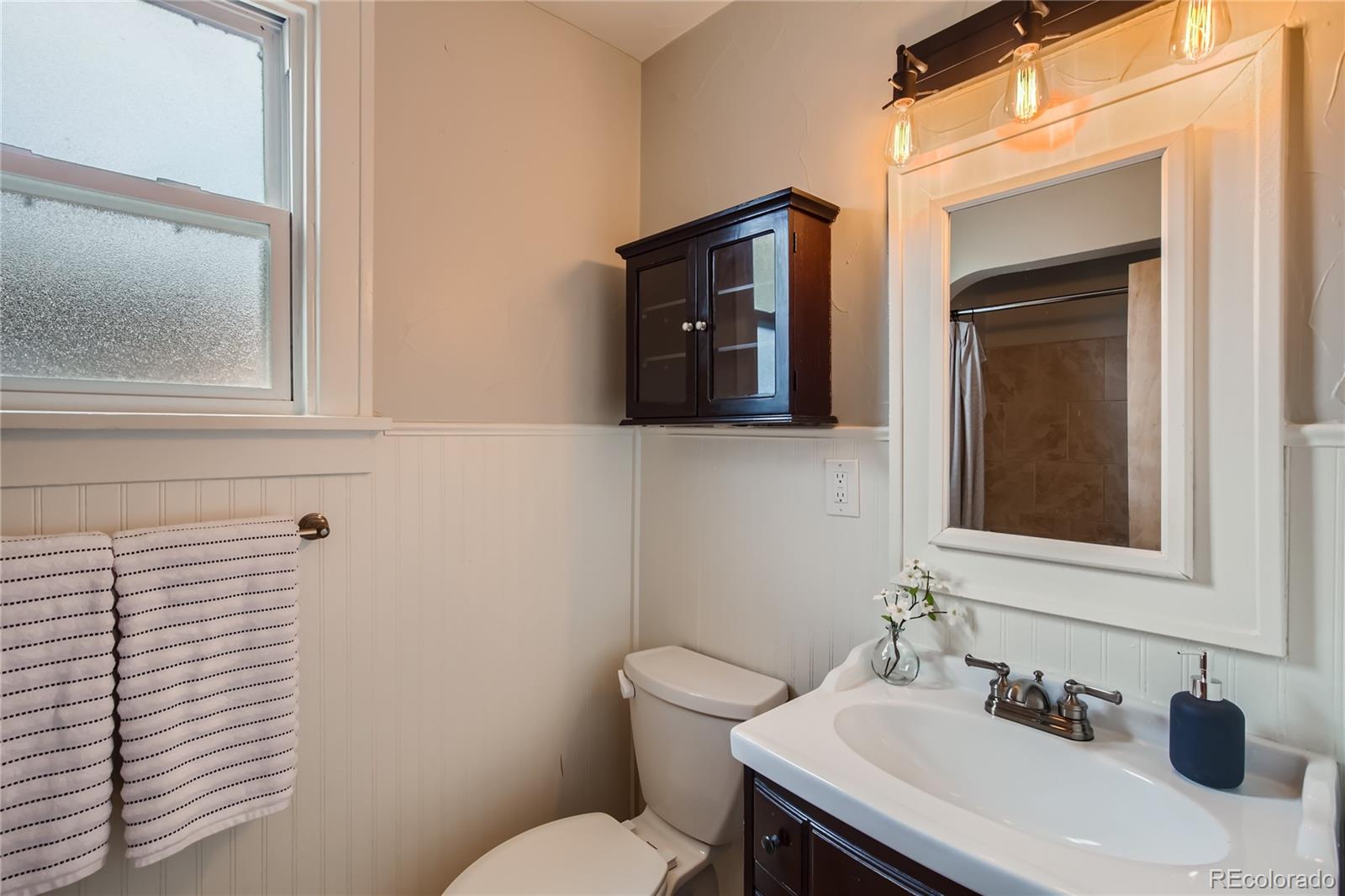 3449 Monroe Street Denver, CO 80205 - Photo 10 of 16 a bathroom with a sink a toilet and mirror