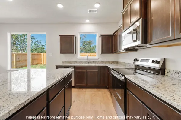 a view of a kitchen with a stove cabinets a ceiling fan and wooden floor