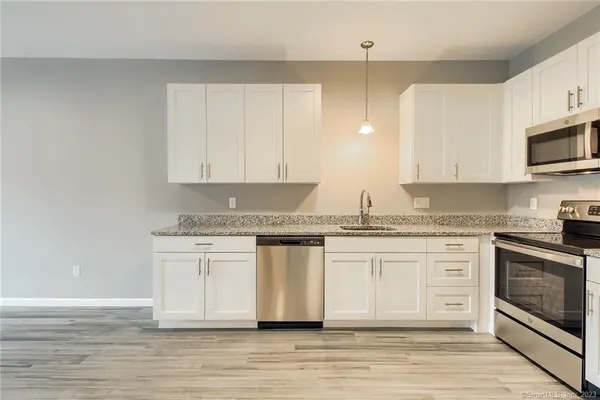 a white kitchen with granite countertop stainless steel appliances