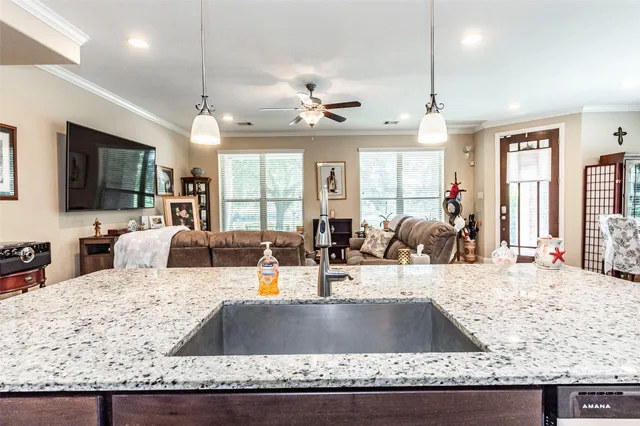 a living room with granite countertop a couch kitchen view and a large window