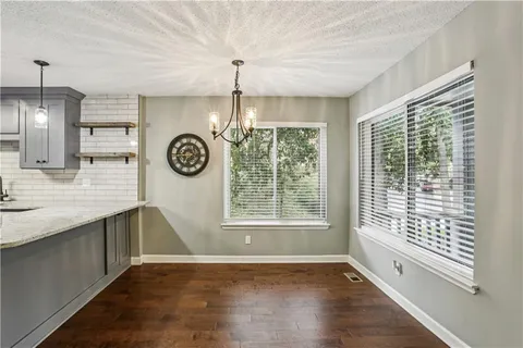 a view of an empty room with window wooden floor and a kitchen