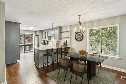 a view of a dining room and livingroom with furniture wooden floor a chandelier