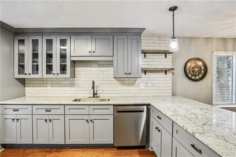 a kitchen with stainless steel appliances granite countertop a sink a stove a clock and cabinets