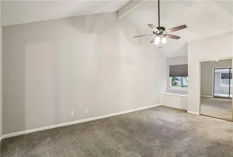 an empty room with a chandelier fan and a kitchen