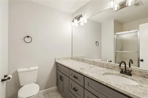a bathroom with a granite countertop sink a toilet and a mirror