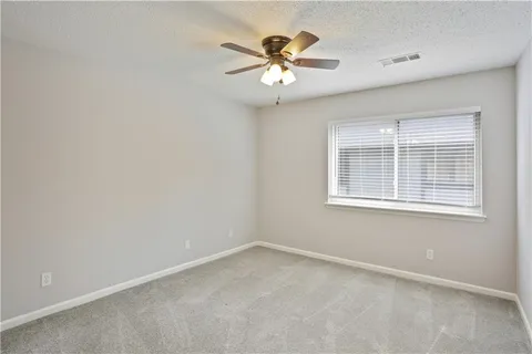 an empty room with window and ceiling fan