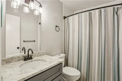 a bathroom with a granite countertop sink toilet and a mirror