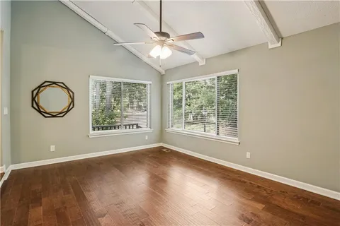 an empty room with wooden floor fan and windows