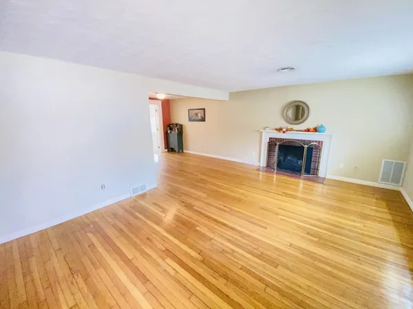 a view of empty room with a fireplace and wooden floor