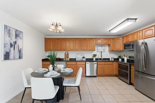 a kitchen with stainless steel appliances granite countertop a stove a sink a refrigerator dining table and chairs
