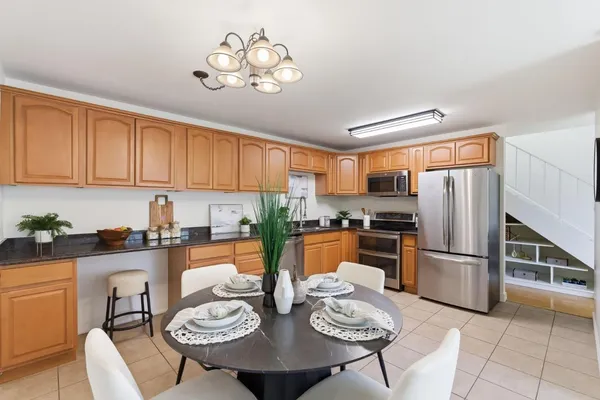 a kitchen with stainless steel appliances granite countertop a refrigerator a sink a stove a dining table and chairs with wooden floor