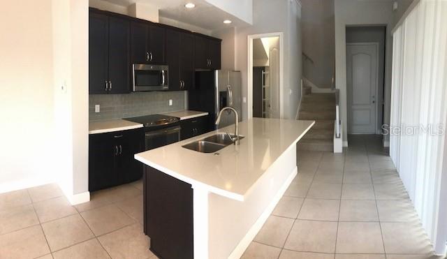 8549 Pinter Street Orlando, FL 32827 - Photo 4 of 25 a kitchen with a sink a counter top space cabinets and stainless steel appliances