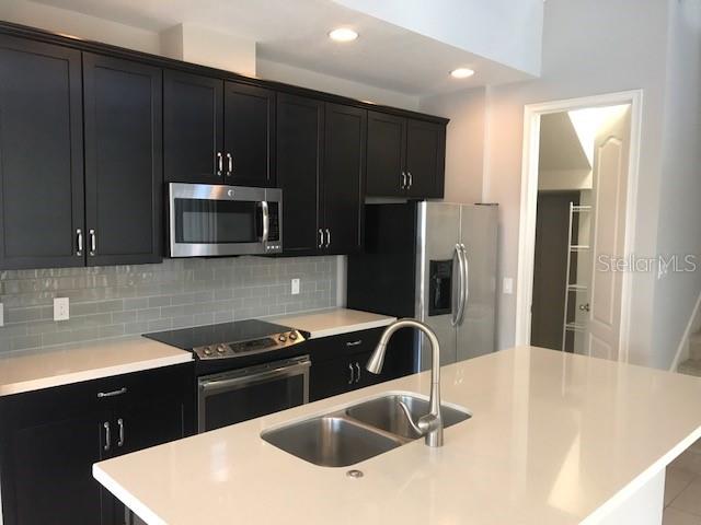 8549 Pinter Street Orlando, FL 32827 - Photo 5 of 25 a kitchen with a sink a counter top space cabinets and stainless steel appliances