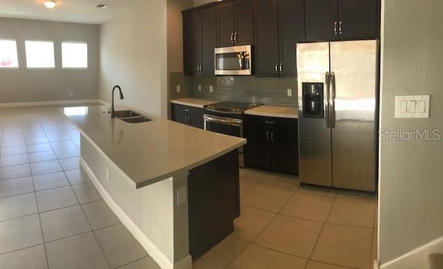 8549 Pinter Street Orlando, FL 32827 - Photo 6 of 25 a kitchen with stainless steel appliances a sink a stove a refrigerator a counter top space and cabinets