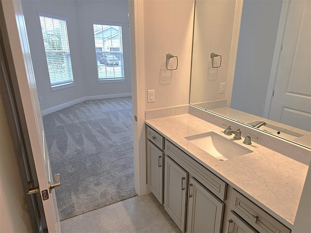 6349 Mossy Oak Road St. Cloud, FL 34771 - Photo 20 of 82 a bathroom with a granite countertop sink a mirror and a shower