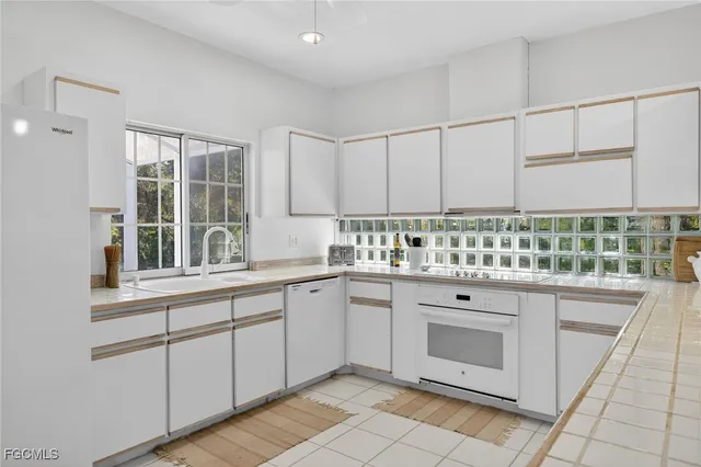a kitchen with granite countertop white cabinets and white appliances