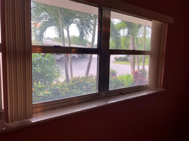 a view of an empty room with wooden floor and windows